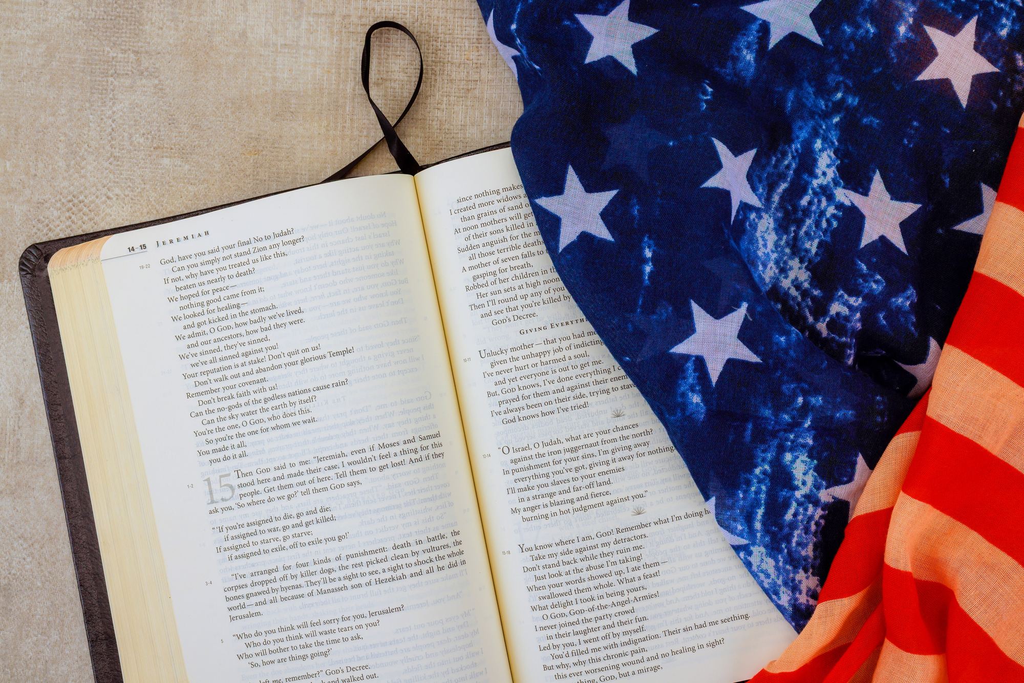 An open Bible turned to the book of Jeremiah, lying beside a folded American flag